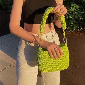 Crocheted acid green bag with a short handle stitched with carabiners